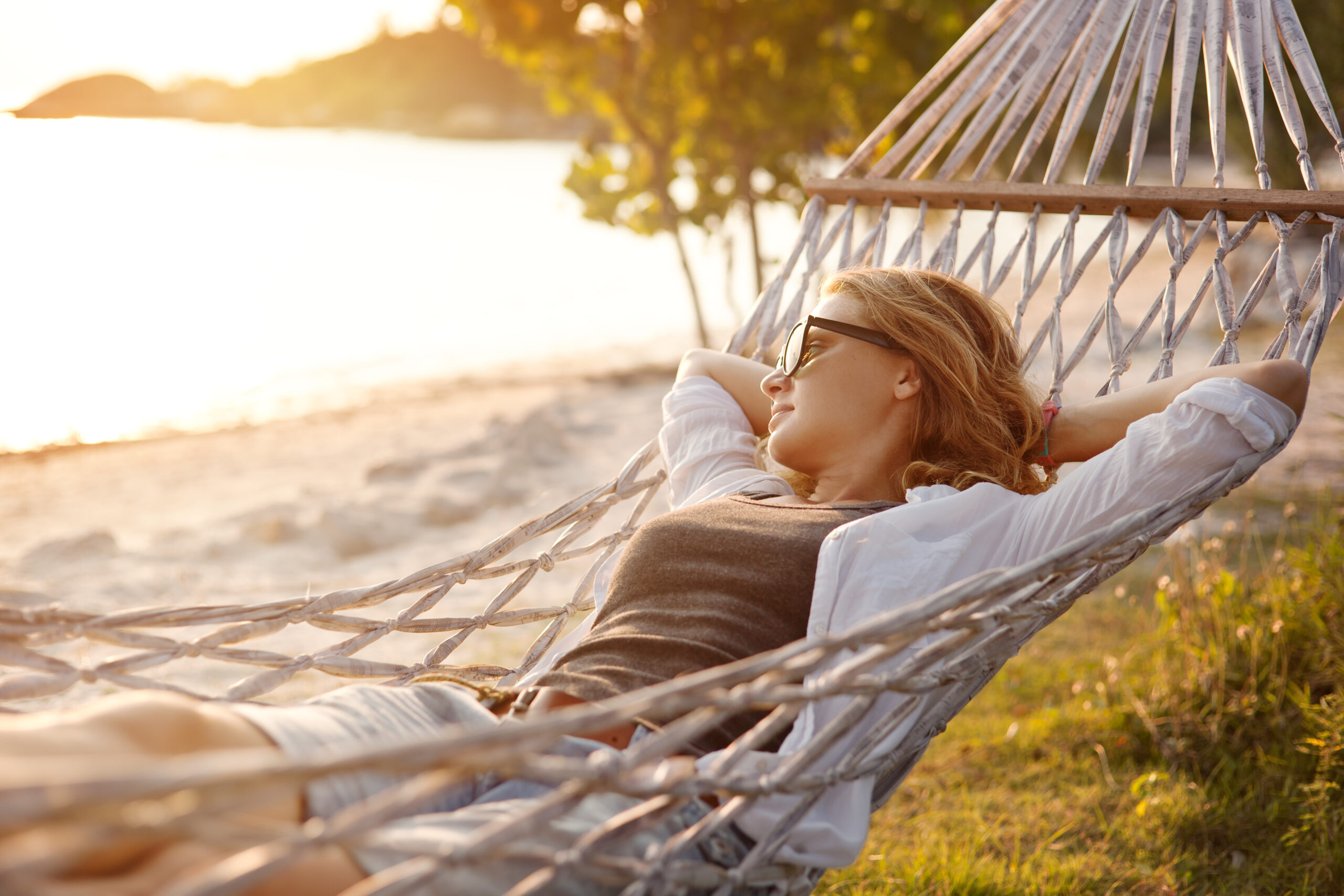 beautiful girl in a hammock on the beach, watching the sunset